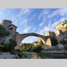 Stari Most w Mostarze podczas wyprawy Caravana Wyjazdy Motocyklowe – zabytkowy most nad rzeką Neretwą otoczony historyczną zabudową.