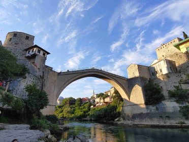 Stari Most w Mostarze podczas wyprawy Caravana Wyjazdy Motocyklowe – zabytkowy most nad rzeką Neretwą otoczony historyczną zabudową.