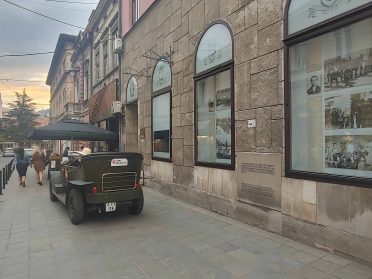 Ulica w Sarajewie podczas wyprawy Caravana Wyjazdy Motocyklowe – zabytkowa architektura, lokalny pojazd i wieczorny klimat miasta.