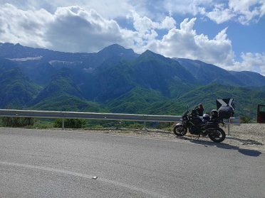 Motocykl i uczestnik na górskiej trasie podczas wyprawy motocyklowej Albania – Macedonia, malownicze bałkańskie krajobrazy.