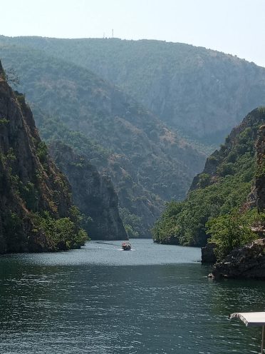 Rejs łodzią w kanionie Matka podczas wyprawy motocyklowej Albania – Macedonia, malownicze klify i spokojna woda Bałkanów.