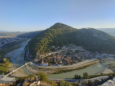 Malownicze bałkańskie miasteczko nad rzeką podczas wyprawy motocyklowej Albania – Macedonia, widok na góry i tradycyjne zabudowania.