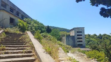 Opuszczony kompleks budynków w górach podczas wyprawy motocyklowej Albania – Macedonia, bałkański klimat i dzikie otoczenie.
