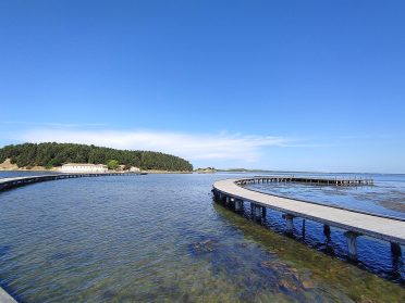 Zakrzywiony pomost nad krystaliczną wodą podczas wyprawy motocyklowej Albania – Macedonia, malownicze bałkańskie wybrzeże.